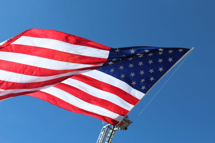 A photograph of the flag of the United States of America flying against a blue sky background