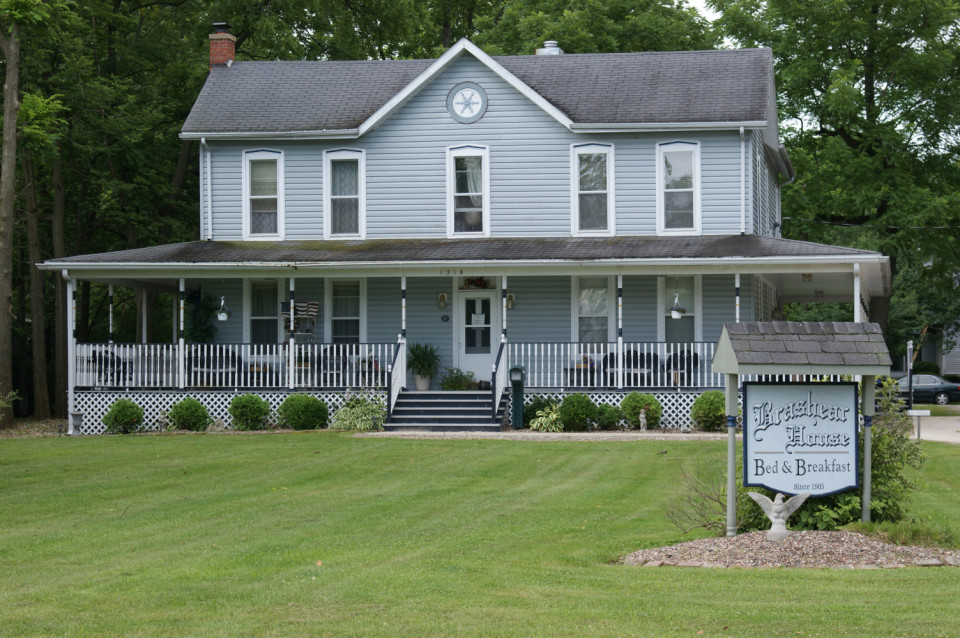 A photograph of the brashear house in brashear, missouri, showcasing its blue siding, early american architecture, and well kept lawn