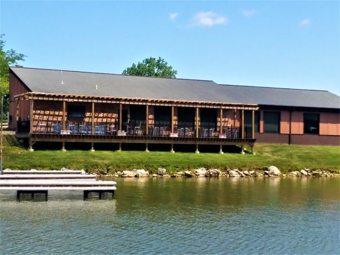 Photograph of the exterior of the dining lodge, showcasing some patio seating and its location on the shore of the lake