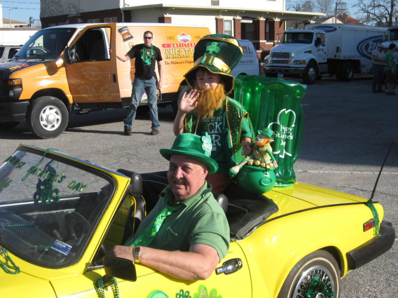 A man and child dressed up in green for St Patrick's Day, in a small yellow car. Celebrating the holiday in Kirksville, Missouri