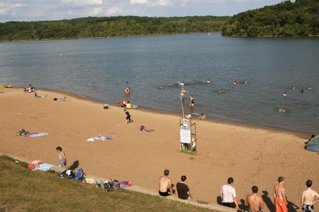 A photograph of the beach at thousand hills state park, with visitors on the beach and in the water